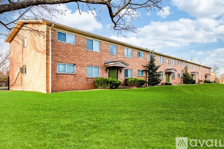 A large brick building with a green lawn in front.