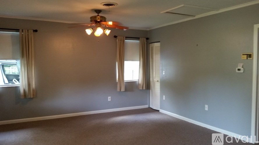 A room with a ceiling fan and carpeted floor.