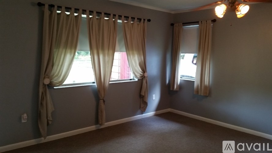 A room with two windows covered by beige curtains.