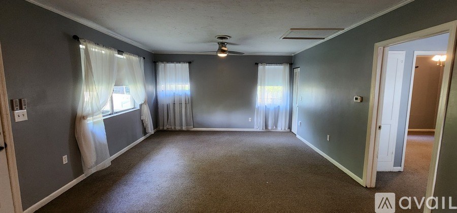 A spacious room with carpeted floor and a ceiling fan.