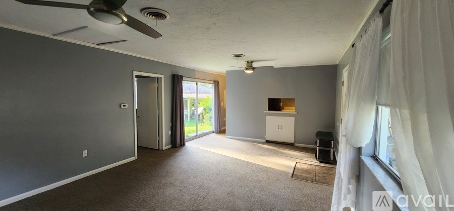 A room with a ceiling fan and a window with curtains.