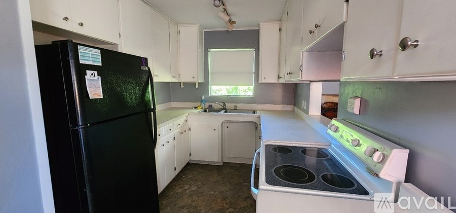 A kitchen with a black fridge and white cabinets.