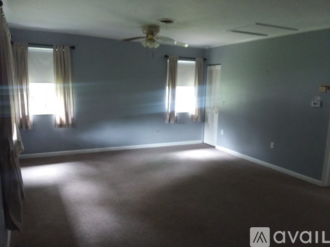 A room with a carpeted floor and a ceiling fan.