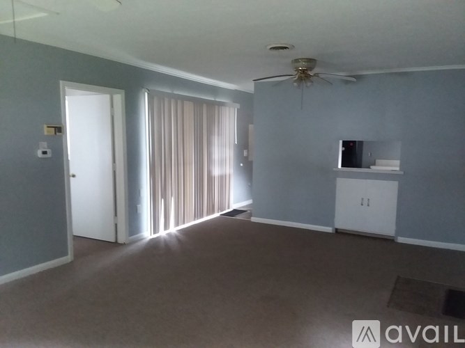 A room with a ceiling fan and a window with curtains.