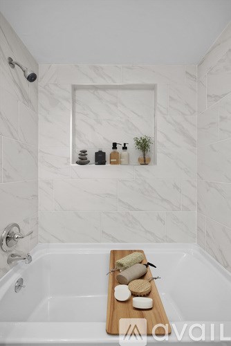 A white bathroom with a tub and a mirror above it.