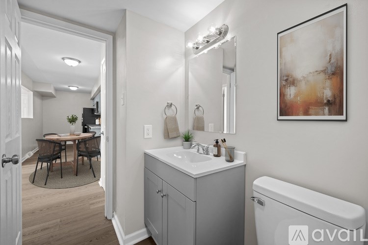 A bathroom with a white toilet, a sink, a mirror, and a painting on the wall.