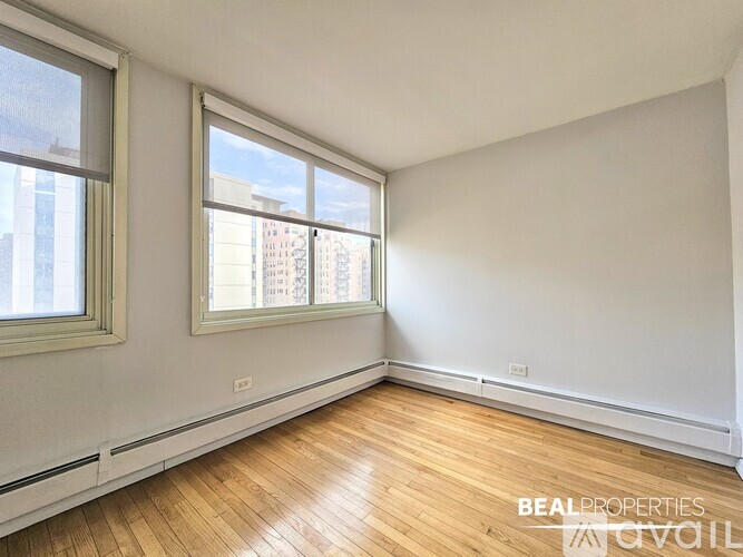 A room with wooden floors and two windows.