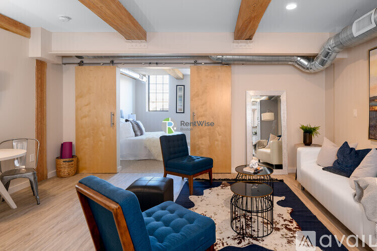 A living room with a white couch, blue chairs, and a rug.