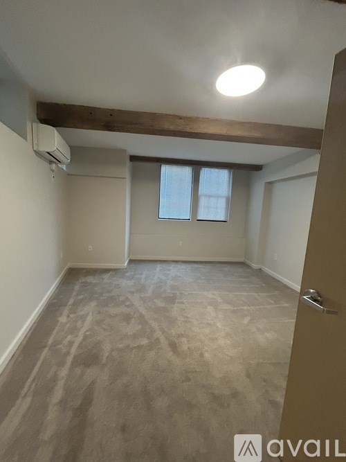 A room with a carpeted floor and a window with blinds.