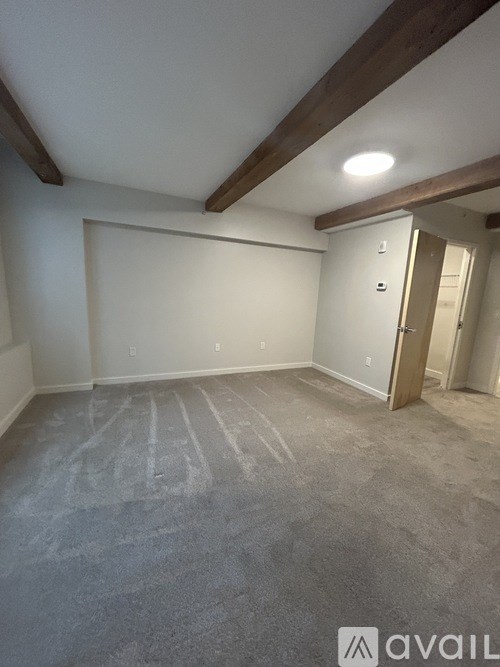 A room with a carpeted floor and a door on the right side.