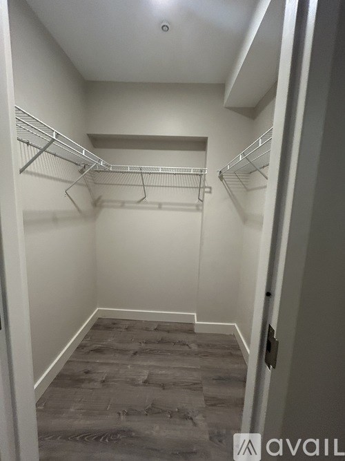 A walk-in closet with a grey carpeted floor and white walls.