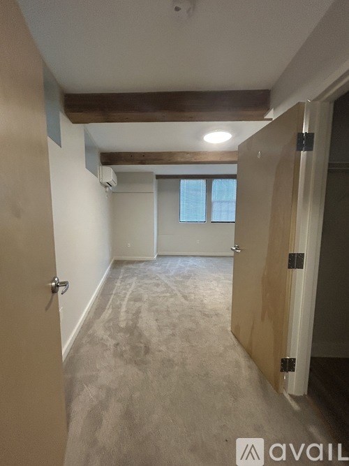 A hallway with a carpeted floor and a door on the left.