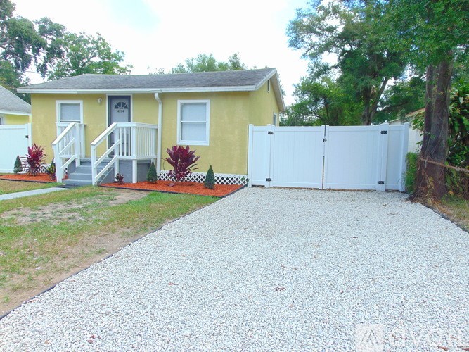 A yellow house with a white fence and gate.