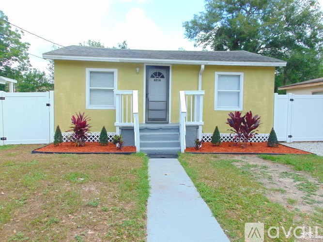 A yellow house with a grey roof and a grey front door.