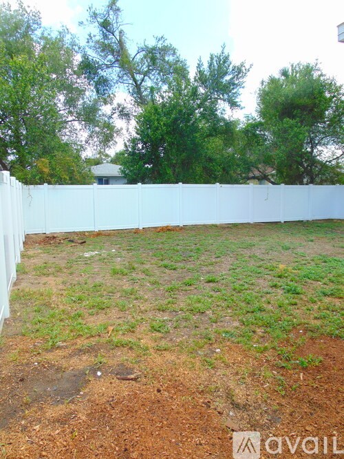 A white fence separates a grassy area from a dirt area.
