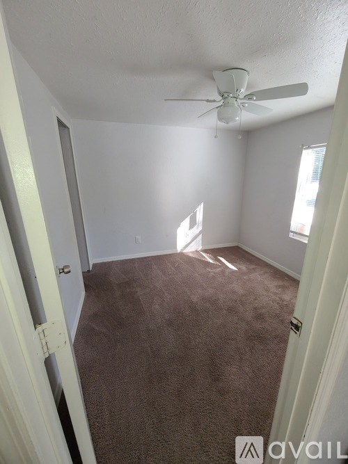 A room with a ceiling fan and carpeted floor.