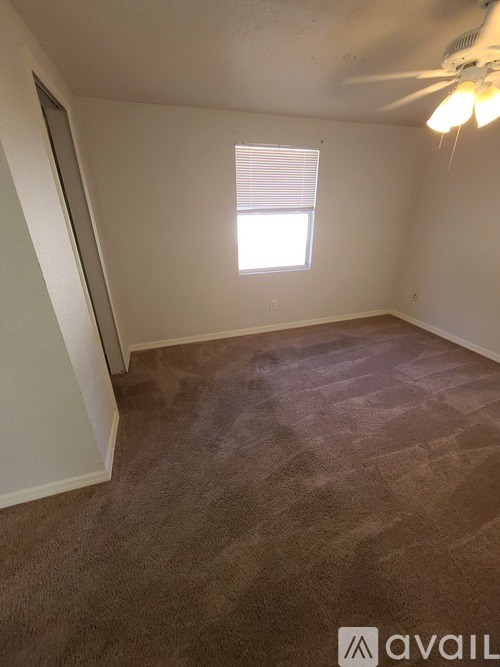 A room with a carpeted floor and a window with blinds.