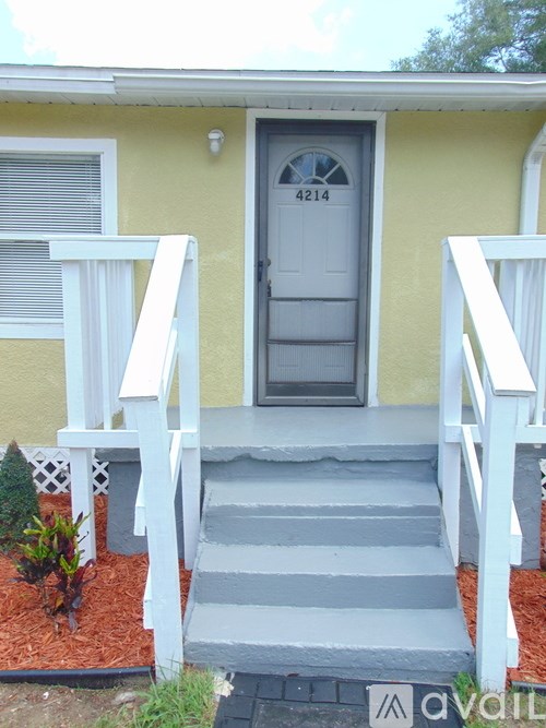 A yellow house with a grey front door and steps.