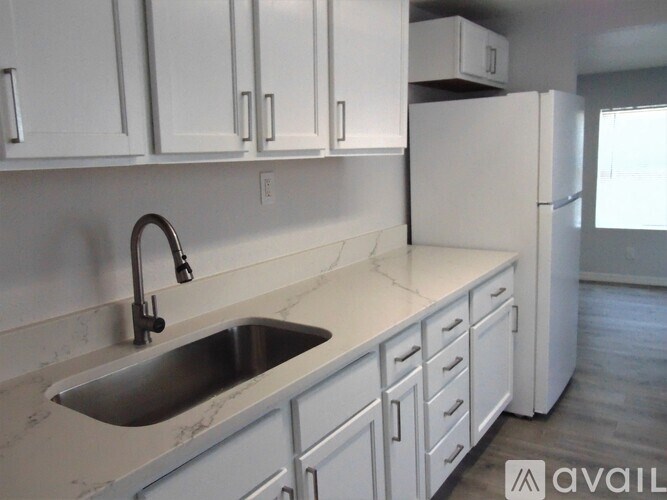 A kitchen with white cabinets and a marble countertop.