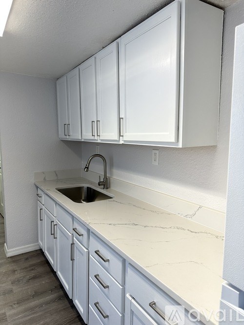 A kitchen with white cabinets and a marble countertop.