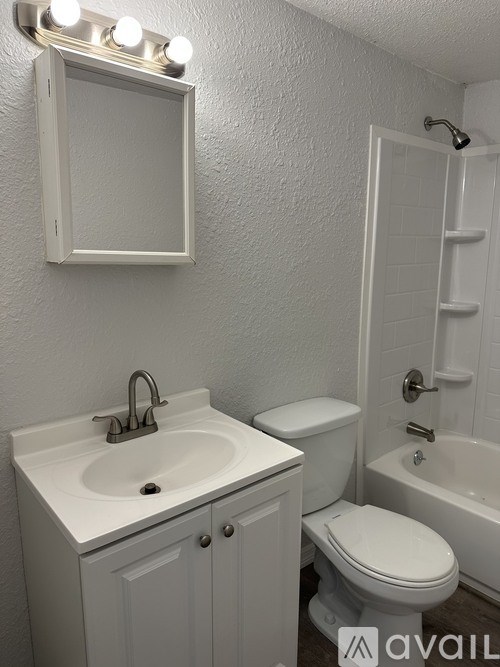 A white bathroom with a toilet, sink, and mirror.