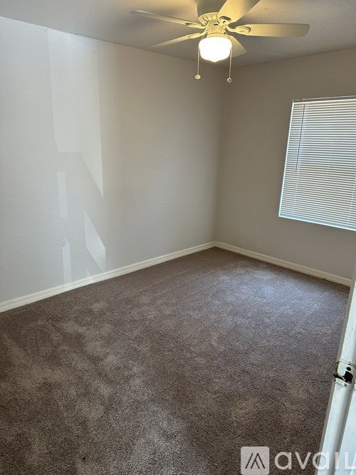 A room with a ceiling fan and carpeted floor.