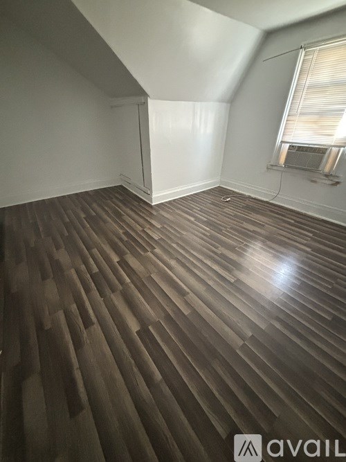 A room with wooden flooring and a window with blinds.