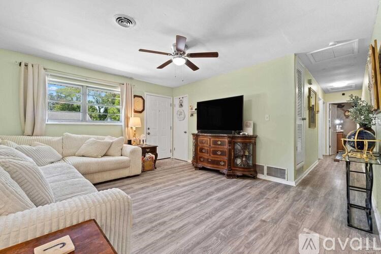 A living room with a white couch, a wooden coffee table, and a flat screen TV.