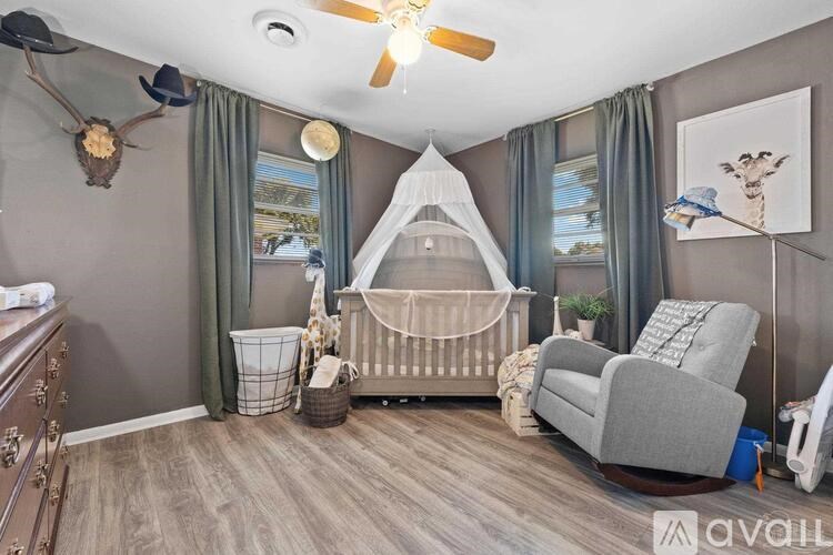 A baby's room with a crib, rocking chair, and a deer head on the wall.