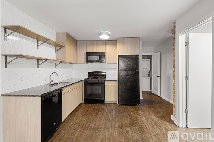 A kitchen with black appliances and wooden floors.