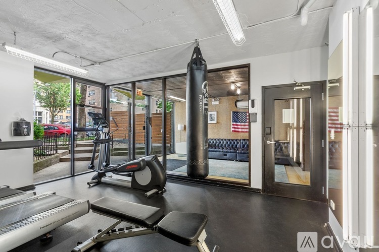 A gym with a treadmill, a rowing machine, a bench, and a punching bag.