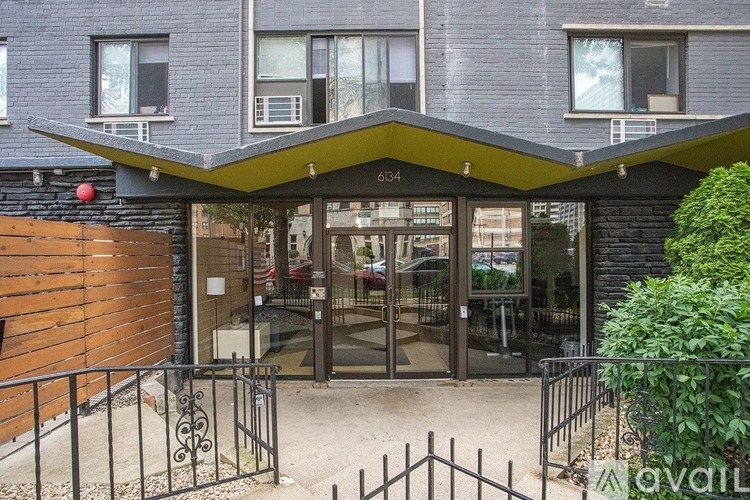 The image shows a building entrance with a glass door and a black gate.