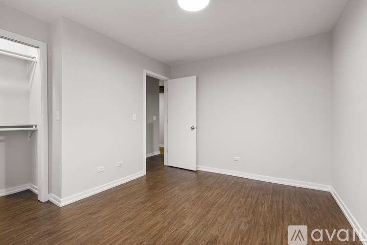 A room with wooden flooring and white walls, with a door on the right side.