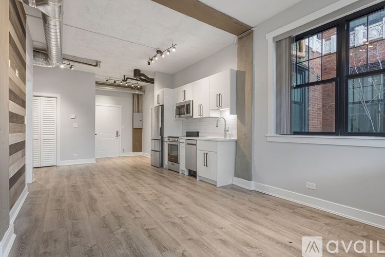 A spacious kitchen with white cabinets and a window overlooking a brick building.