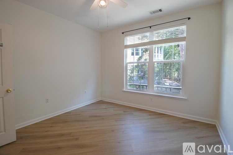 A room with wooden flooring and a window with blinds.