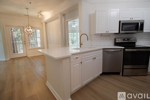 A kitchen with white cabinets and a wooden floor.