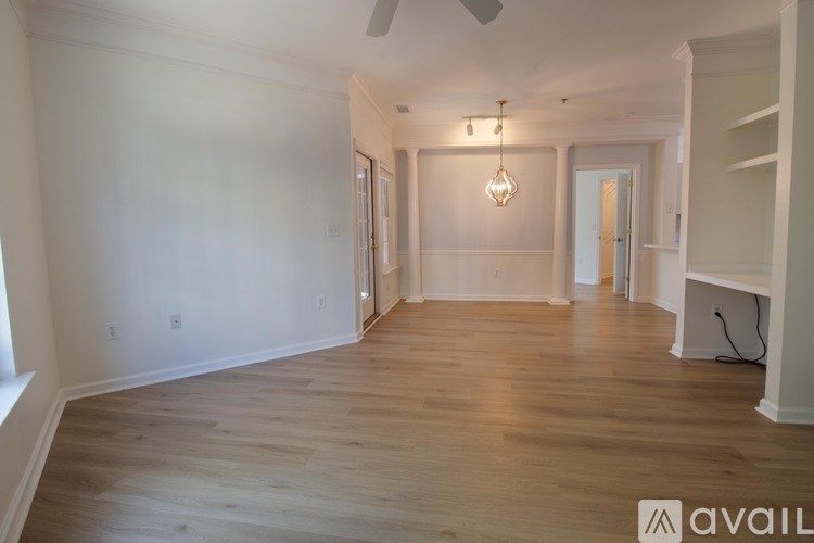 A spacious room with wooden flooring and a ceiling fan.