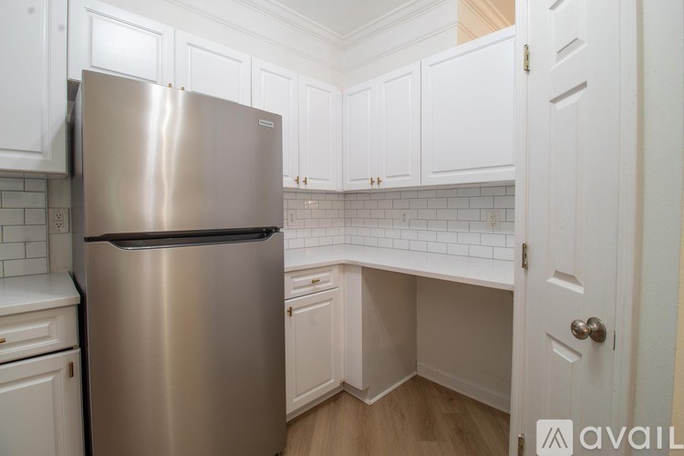 A stainless steel refrigerator in a kitchen with white cabinets.