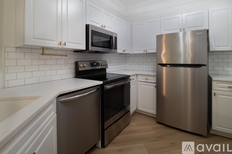 A kitchen with white cabinets and a stainless steel refrigerator.