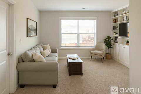 A living room with a grey couch, a chair, a coffee table, and a painting on the wall.