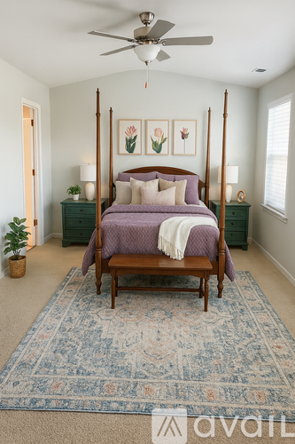 A bedroom with a four poster bed and a rug on the floor.