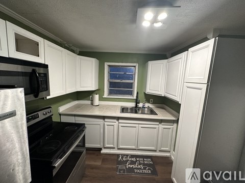 A kitchen with white cabinets and a black stove top oven.