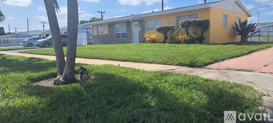 A tree in a grassy area in front of a yellow house.