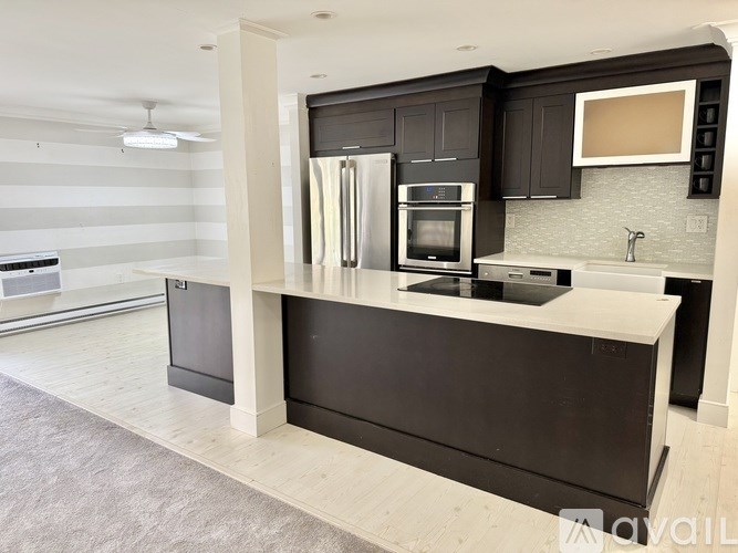 A modern kitchen with black cabinets and a white countertop.