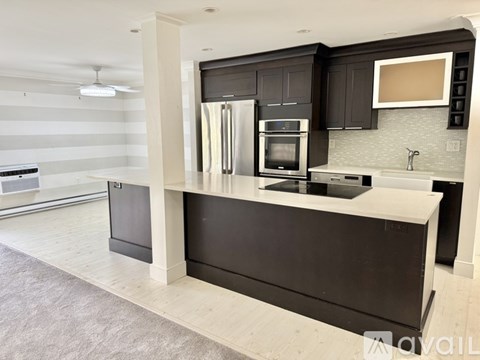 A modern kitchen with black cabinets and a white countertop.