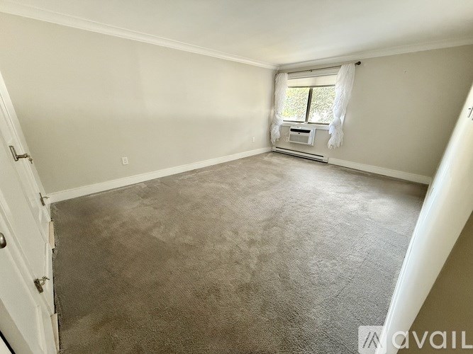 A room with a carpeted floor and a window with curtains.