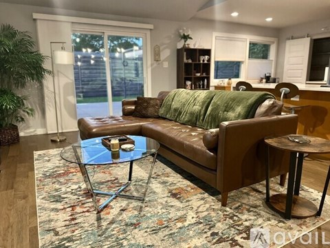 A living room with a brown couch and a glass coffee table.