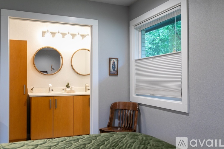 A bedroom with a bed, a chair, and a medicine cabinet with a mirror above it.