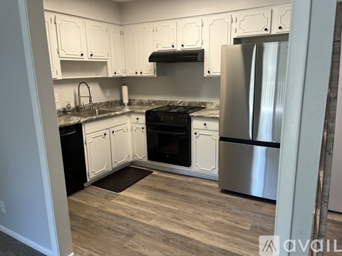 A kitchen with white cabinets and a stainless steel refrigerator.