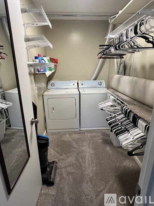 A laundry room with a washer and dryer, a mirror, and clothes hanging up.